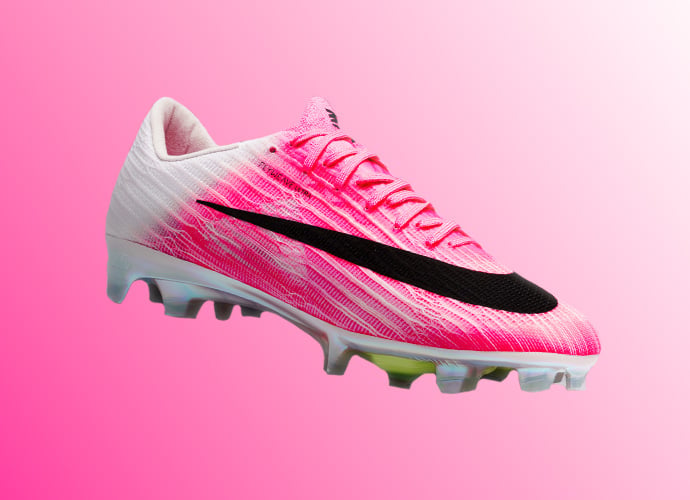 Nike Mercurial Vapor low-cut soccer cleat in white pink ombre gradient with black swoosh branding and AG-Pro studs on matching pink backdrop