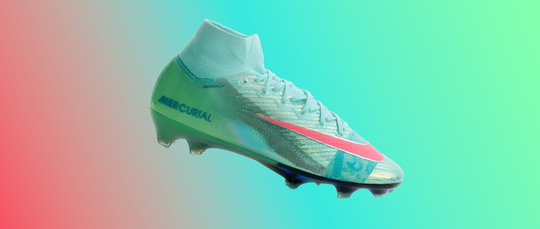Nike Mercurial Superfly football boot in mint green turquoise with coral pink swoosh, blue Mercurial branding and FG studs on pink turquoise gradient background