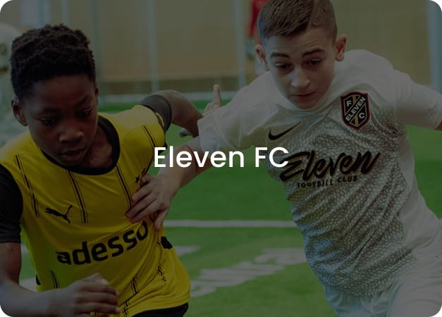 Two boys competing for the ball in yellow and white football kits - Eleven FC youth football club at 11teamsports Academy