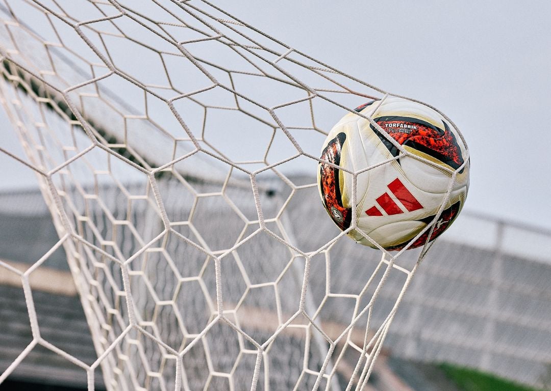 adidas Torfabrik match ball in goal net showing red adidas stripes and Torfabrik branding - official Bundesliga football