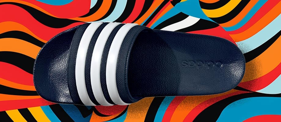 adidas Cloadfoam Adilette Regular in dunklem Legend Ink Blau in Aufsicht mit Blick auf den den Riemen mit eingeprägten adidas 3-Stripes vor einem bunten Wellenlinienhintergrund