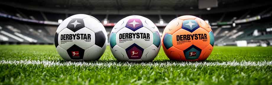 Derbystar Brillant APS Bundesliga Bälle aus Saison 2023/2024 auf dem Stadionrasen, zu sehen sind die drei verfügbaren Versionen Classic in Weiß-Schwarz,  der farbige Official Match Ball und der orangene Winterball