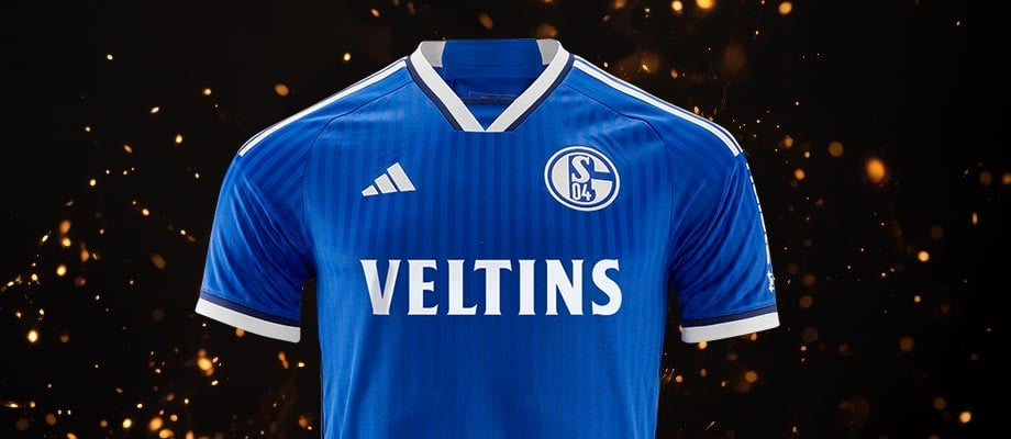 adidas FC Schalke 04 Trikot Home 2023/2024 Blau Weiß vor schwarzem Hintergrund mit gelb weiß sprühenden Funken zur Feier des noch rechtzeitig gefundenen Hauptsponsors VELTINS für Saison 2023/2024