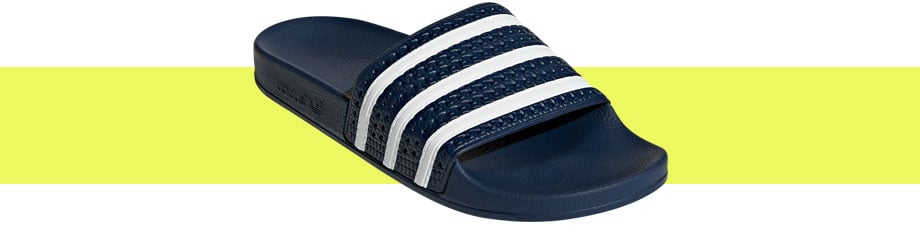 adidas Originals Adilette Blau Weiß, diagonaler Blick von vorne auf die Badelatsche mit direkter Sicht auf den texturierten Riemen mit den klassischen drei adidas-Streifen