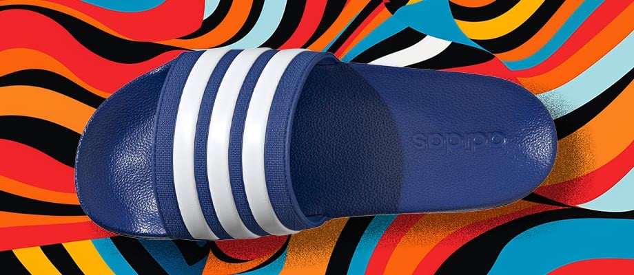adidas Cloadfoam Adilette Regular in Blau in Aufsicht mit Blick auf den den Riemen mit eingeprägten adidas 3-Stripes vor einem bunten Wellenlinienhintergrund