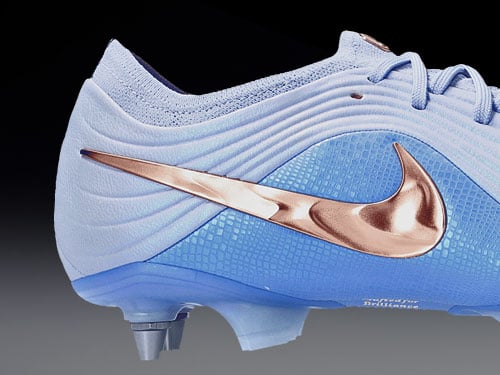 Gros plan sur le swoosh plaqu&eacute; cuivre brillant du mod&egrave;le Tiempo Maestro Elite