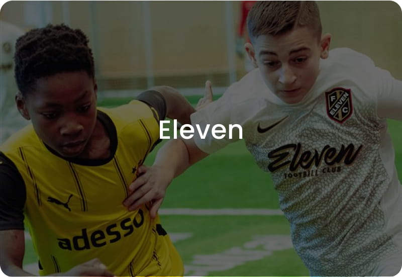 Two boys competing for the ball in yellow and white football kits - Eleven FC youth football club at 11teamsports Academy