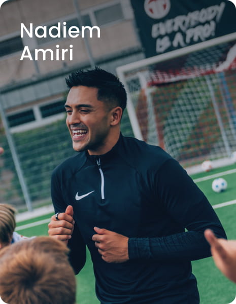 German international Nadiem Amiri posing with young boy in blue football kit - 11teamsports Football Academy ambassador