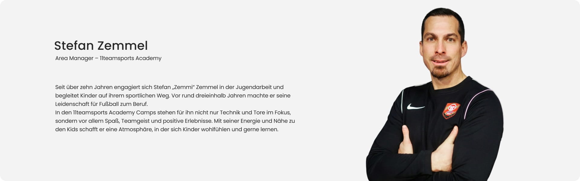 Stefan Zemmi Zemmel, Area Manager at 11teamsports Academy, smiling with arms crossed in black Nike long-sleeve shirt with Academy badge