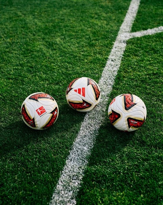 Three adidas Torfabrik footballs on stadium pitch with white corner line - official Bundesliga match balls with red adidas logo and white panels