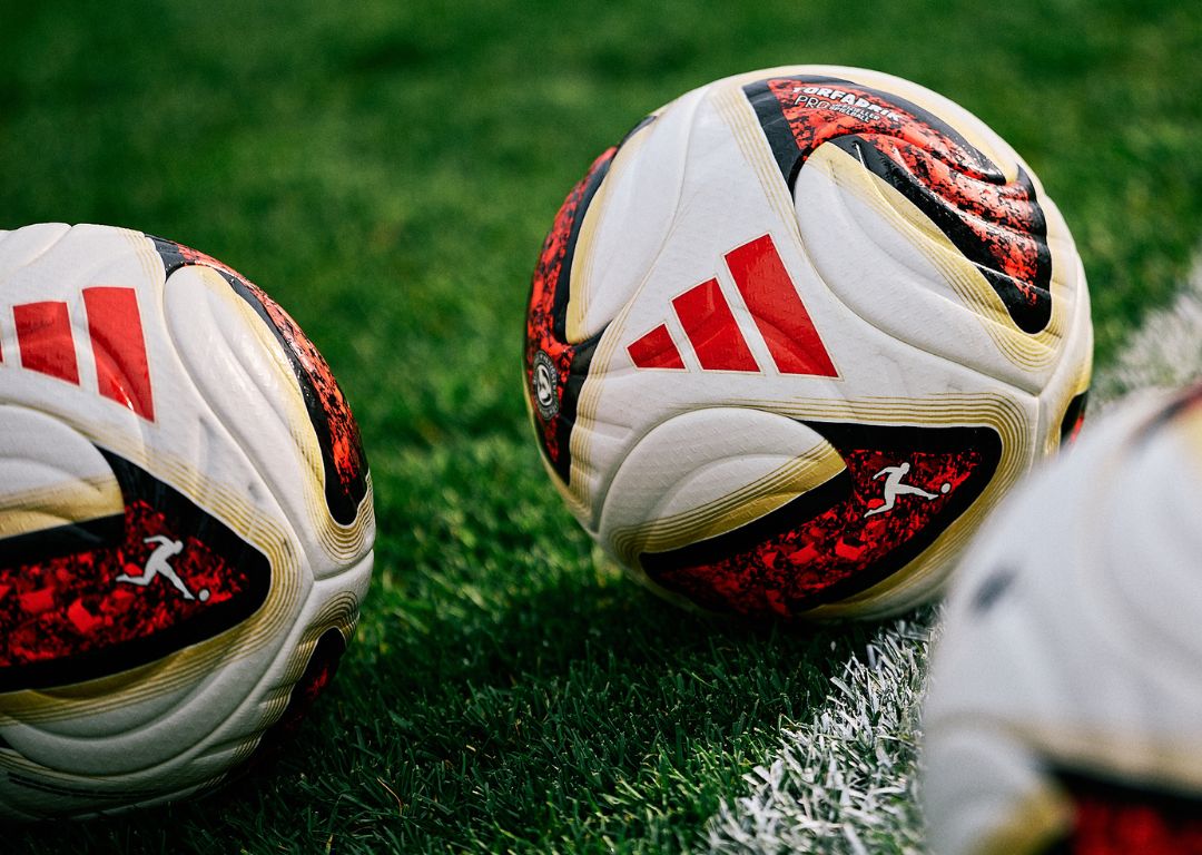 adidas Torfabrik footballs on stadium pitch with white line markings - official Bundesliga match balls with red and gold design