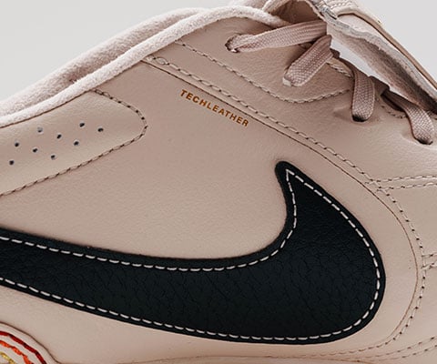 Gros plan sur le c&ocirc;t&eacute; lat&eacute;ral avec Swoosh et TECHLEATHER imprim&eacute; en lettres dor&eacute;es au-dessus