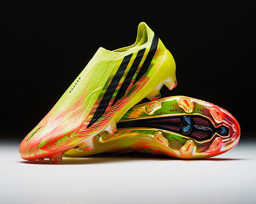 Pair of the adidas F50 Hyperfast Elite LL FG first launch edition boots arranged: one sideways showing the sole plate. Other boot on top showing lateral outside profile with F50 style streamlined adidas 3-stripes