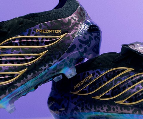 Gros plan sur le c&ocirc;t&eacute; lat&eacute;ral ext&eacute;rieur avec le motif pr&eacute;f&eacute;r&eacute; de Kak&aacute; d'un jaguar et les 3-Bandes style Predator adidas dor&eacute;es, le collier tricot&eacute; est partiellement visible