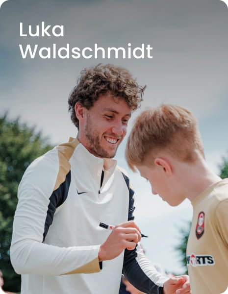 German international Luka Waldschmidt posing with young boy in white football kit - 11teamsports Football Academy ambassador