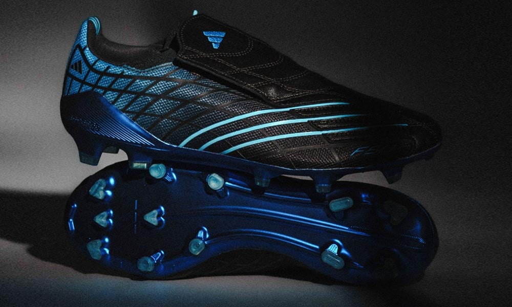 Ein Paar Limited Edtion adidas F50 Spider FG Fu&szlig;ballschuhe als Fotostudioshot mit hartem Licht, aufeinandergestapelt. Ein Schuh auf die Seite gestellt f&uuml;r den direkten Blick auf die Sohle. Der zweite Schuh darauf stehend und den Au&szlig;enrist mit Spiderweb und den drei d&uuml;nnen blauen Streifen zeigend mit einem Hauch des Leder-Covers &uuml;ber der Schn&uuml;rung