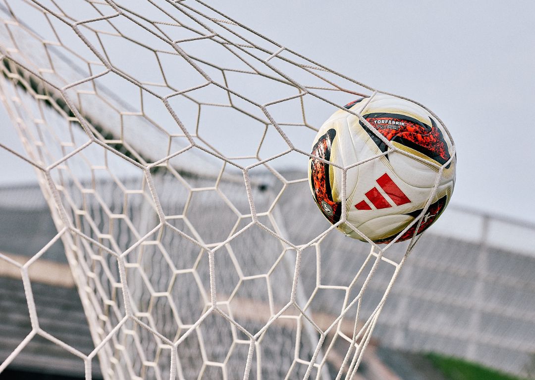 adidas Torfabrik match ball in goal net showing red adidas stripes and Torfabrik branding - official Bundesliga football