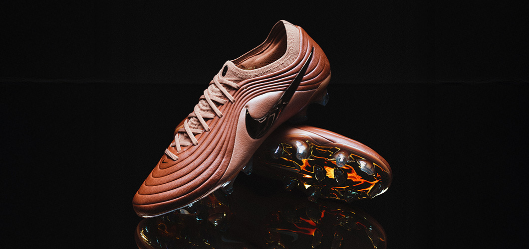 Nike Tiempo Maestro football boots in rose gold/copper finish showcasing wavy ribbed upper design and reflective soleplate with colorful metallic studs against black background with reflection