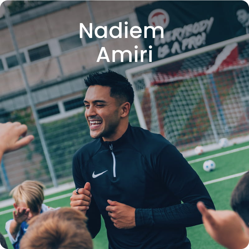 German international Nadiem Amiri posing with young boy in blue football kit - 11teamsports Football Academy ambassador