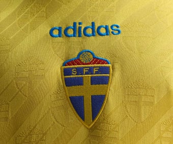 Embroidered SvFF federation emblem and adidas Trefoil logo on chest of the Sweden 1994 home jersey